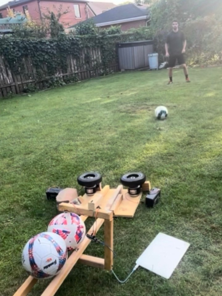 Wooden football passing machine with two motorised wheels firing a ball across a yard